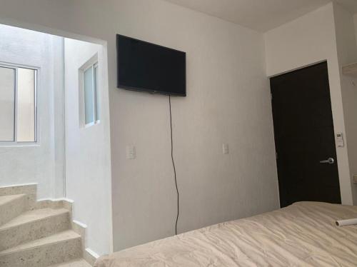 a bedroom with a bed and a flat screen tv on the wall at Spacious house with Acapulco club in Acapulco