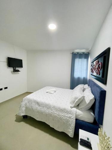 a bedroom with a white bed and a tv at Apartahotel MKS Caribe in San Andrés