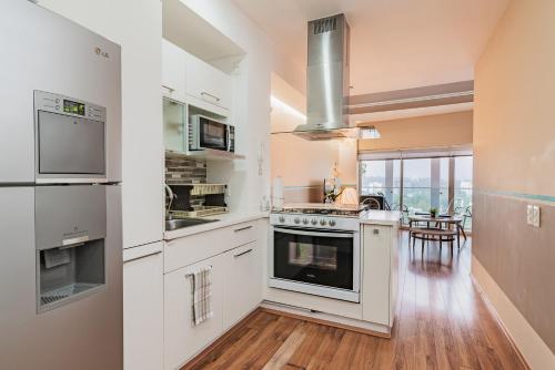 a kitchen with white appliances and a dining room at TOP VIEW PENTHOUSE Private Rooftop, Wi-Fi 500Mbps, Air Conditioning, Grill, Pool and Gym in Mexico City