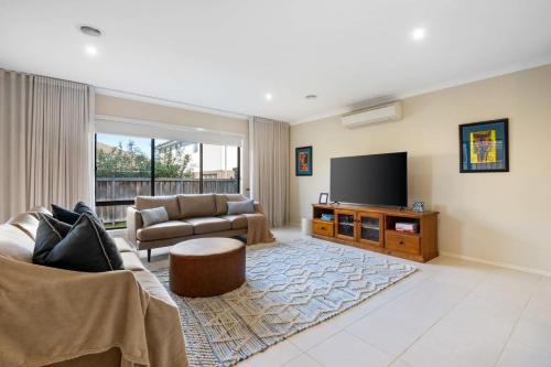 a living room with a couch and a flat screen tv at North Geelong Getaway Modern 4-Bedroom Home in Hamlyn Heights