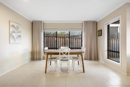 a dining room with a table and chairs and windows at North Geelong Getaway Modern 4-Bedroom Home in Hamlyn Heights