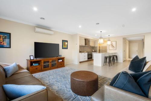 a living room with a couch and a flat screen tv at North Geelong Getaway Modern 4-Bedroom Home in Hamlyn Heights