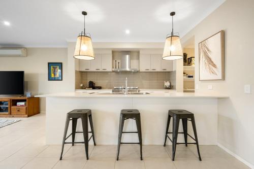 a kitchen with two bar stools at a kitchen counter at North Geelong Getaway Modern 4-Bedroom Home in Hamlyn Heights