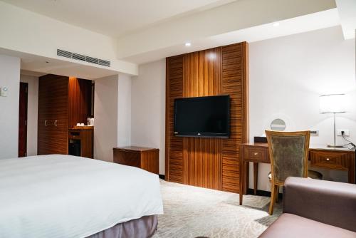 a hotel room with a bed and a flat screen tv at Arsma Hotel in Hualien City
