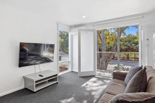 a living room with a couch and a tv at Bungala Cottage 28 Jetty Road in Normanville