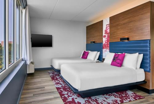 a hotel room with two beds and a flat screen tv at Aloft Raleigh in Raleigh