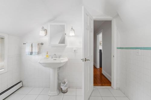 a white bathroom with a sink and a shower at Harbor Walk Charming 4BR Steps to Town & Harbor in Barrington