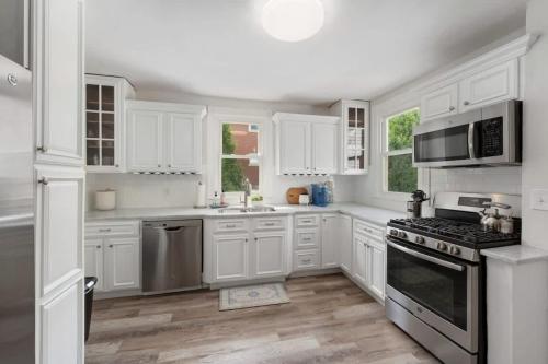 a kitchen with white cabinets and stainless steel appliances at Harbor Walk Charming 4BR Steps to Town & Harbor in Barrington