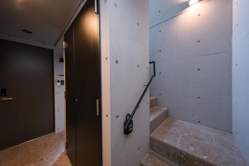 a hallway with stairs and a door with a hand rail at ZAITO Waseda Terra Hotel in Tokyo