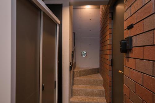 a hallway with a brick wall and stairs with a shower at ZAITO Waseda Terra Hotel in Tokyo