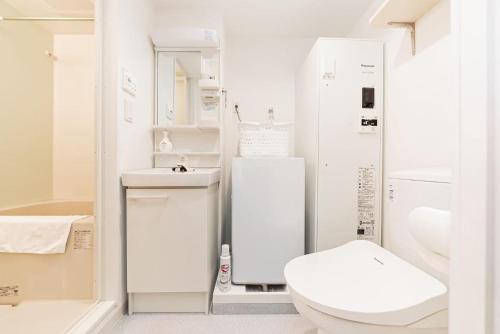 a white bathroom with a toilet and a sink at shinjuku house in Tokyo