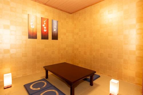 a room with a table and three paintings on the wall at Stay KobeA in Kobe