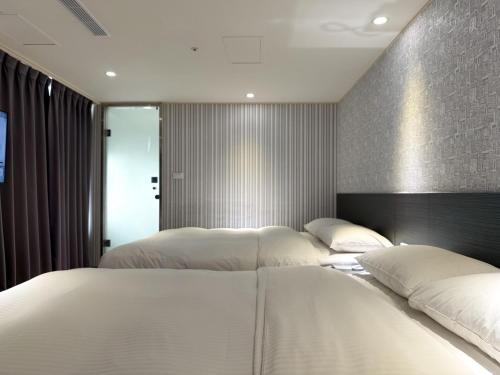 a bedroom with two beds with white pillows at 雋格大飯店 Elence Hotel in Taichung