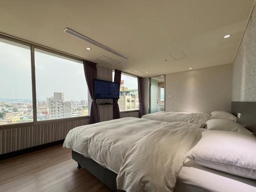 a bedroom with two beds and a flat screen tv at 雋格大飯店 Elence Hotel in Taichung