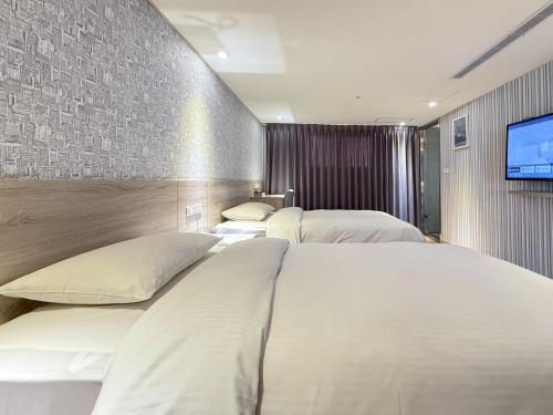 a hotel room with two beds and a flat screen tv at 雋格大飯店 Elence Hotel in Taichung