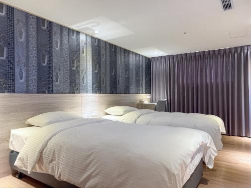 two beds in a hotel room with a wall with at 雋格大飯店 Elence Hotel in Taichung