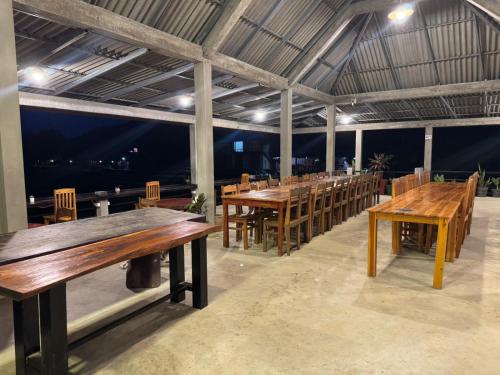 a row of wooden tables and chairs in a room at ເຂົ້າໜຽວຟາມສະເຕ-Kao Niaw Farmstay in Luang Prabang