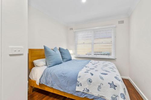 a bedroom with a bed with blue pillows and a window at Seahaven at Mossy in Mossy Point