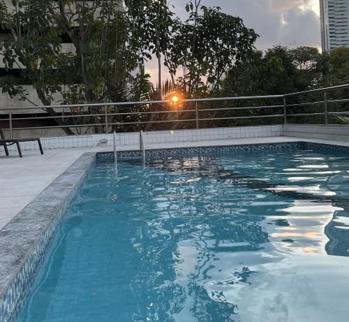 a swimming pool with the sun setting in the background at Flat Parque da Jaqueira in Recife