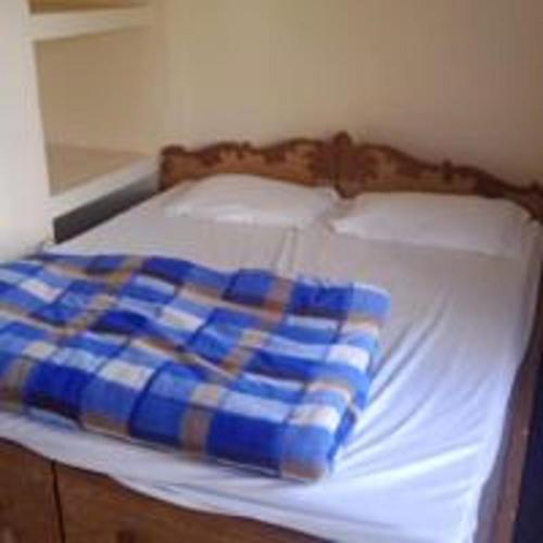 a bed with a blue and white blanket on it at Dana Pani Homestay by StayApart in Ukhimath