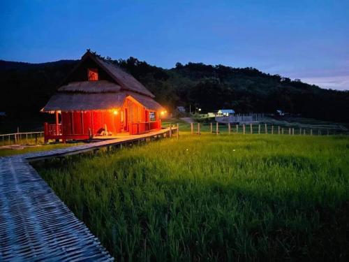 a red building in a field next to a field of grass at ເຂົ້າໜຽວຟາມສະເຕ-Kao Niaw Farmstay in Luang Prabang