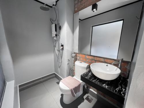 a bathroom with a sink and a toilet and a mirror at A Coral Reefs Resort Langkawi by Manhattan Group in Pulau Chupak