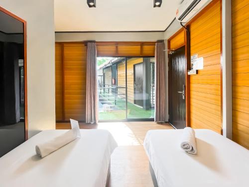 two white beds in a room with sliding glass doors at A Coral Reefs Resort Langkawi by Manhattan Group in Pulau Chupak