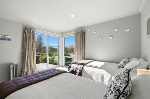 two beds in a room with a window at Hurunui River Retreat - Flax Cottage in Hurunui