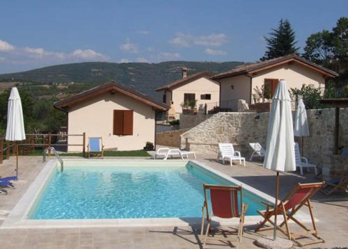 a swimming pool with chairs and umbrellas next to a house at Valleprata in Sellano