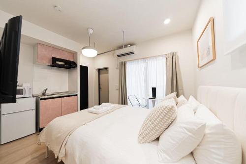 a bedroom with a white bed and a kitchen at shinjuku house in Tokyo