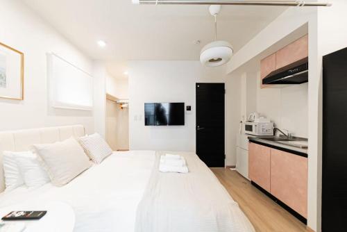 a large white bed in a room with a kitchen at shinjuku house in Tokyo