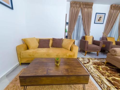 a living room with a yellow couch and a coffee table at Morgan Hill Residence in Abuja