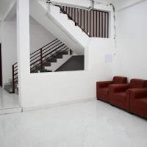 a living room with a red couch and stairs at Hotel The Yamuna by StayApart in Kharsālī