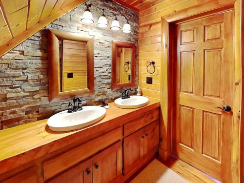 a bathroom with two sinks and a stone wall at Crows Point Lakehouse in Swanton