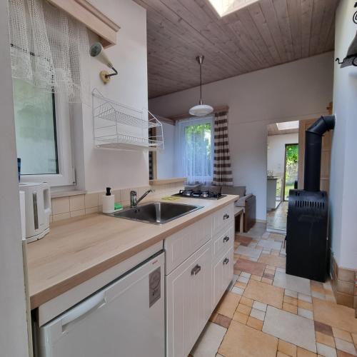 a kitchen with white cabinets and a sink at Pokoje i apartamenty przy Sosnowej in Poddąbie