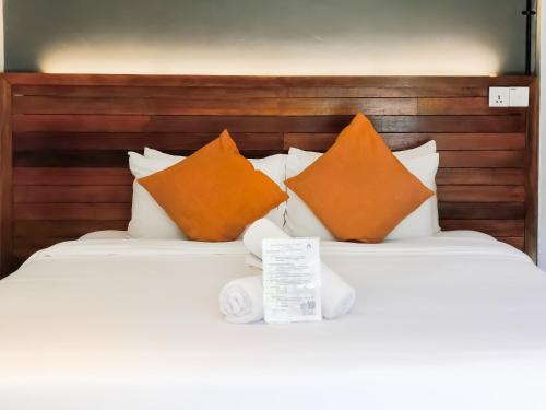 a bed with orange and white pillows on it at A Coral Reefs Resort Langkawi by Manhattan Group in Pulau Chupak