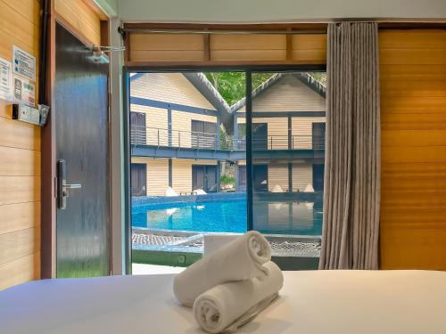 a towel sitting on a bed in front of a window at A Coral Reefs Resort Langkawi by Manhattan Group in Pulau Chupak