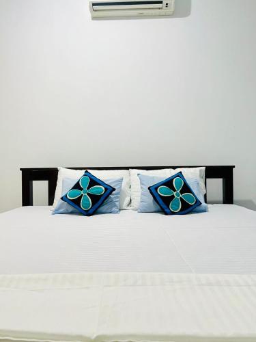 a white bed with blue pillows on it at Udawalawa Eco Lodge in Udawalawe