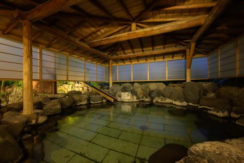 a pool of water in a building with rocks at Senkeien Tsukioka Hotel in Kaminoyama