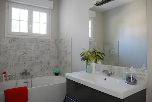 a bathroom with a white tub and a sink and a bath tubermott at Maison Aux Portes Du Médoc in Arsac