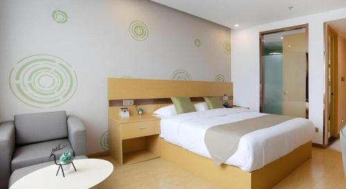 a bedroom with a large bed and a chair at GreenTree Inn Linhai Jiangnan Avenue Express in Linhai