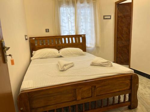 蓬蒂切里Rhythm Stay Pondicherry的一张大木床,上面有两条白色毛巾