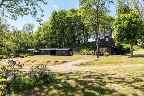 a black house in a field with trees at Beautiful House In Fantastic Surroundings in Nykøbing Mors