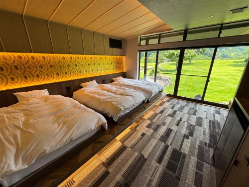 three beds in a room with a large window at waku terrace in Fukui