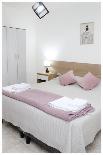 a bedroom with a large white bed with pink towels on it at VL Apart in Villa Regina