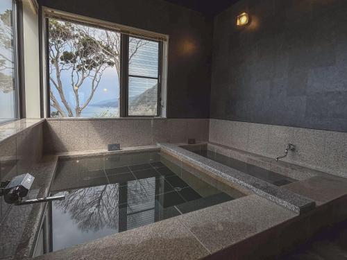 a large bathroom with a large tub with a window at waku terrace in Fukui