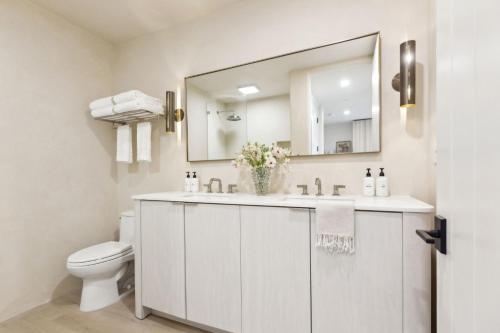 a bathroom with a sink and a toilet and a mirror at Casa Riviera - Boutique Apartments in Downtown Santa Barbara in Santa Barbara