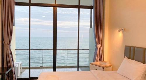 a bedroom with a large window with a view of the ocean at Phala Shore Resort in Ban Phala