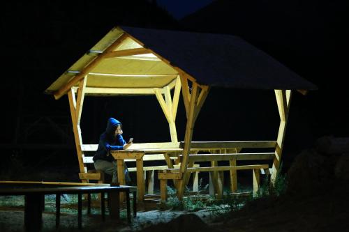 a woman sitting at a table in a gazebo at night at Отдых в комфортабельных юртах в зоне отдыха Kolsay resort! in Kurmenty