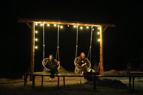two people sitting on a swing at night at Отдых в комфортабельных юртах в зоне отдыха Kolsay resort! in Kurmenty